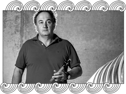 Egly-Ouriet, Champagne winemaker, holding a wine thief beside stainless tanks, framed with Dynamic Cellars wave design