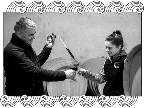 Domaine Felettig winemakers drawing wine from barrel in their Chambolle-Musigny cellar, framed with Dynamic Cellars wave desi