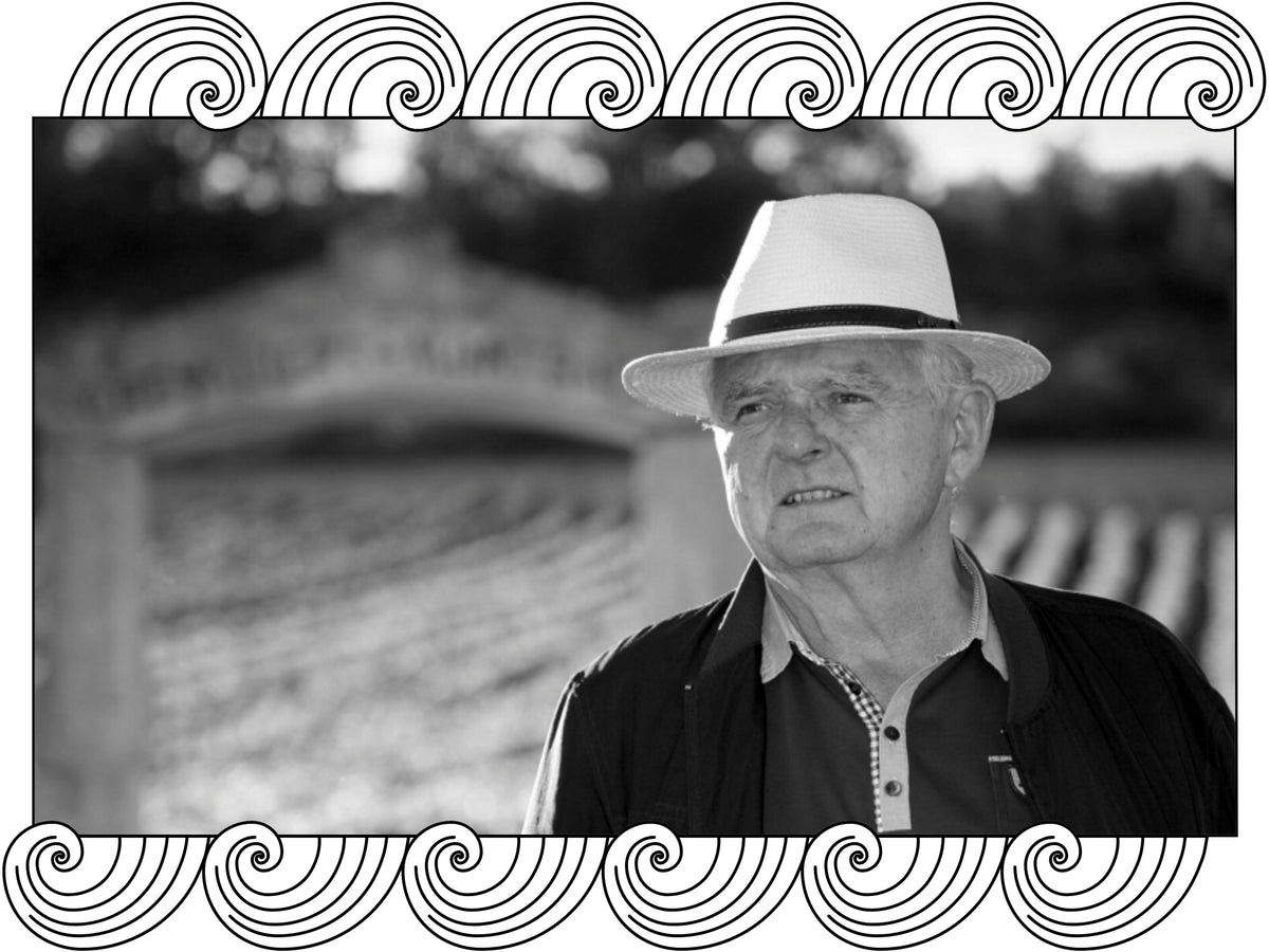 Domaine Olivier Leflaive: the winemaker in a hat by the estate's entrance gate, framed with Dynamic Cellars wave design