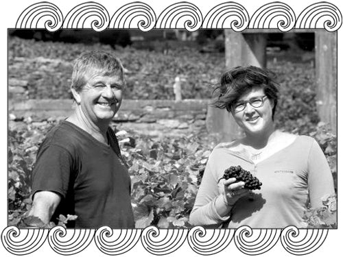 Domaine Armand Rousseau winemakers holding grapes in their Burgundy vineyard, framed with Dynamic Cellars wave design