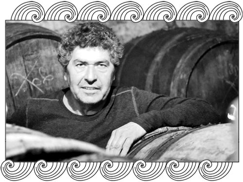 Domaine Rousset Peyraguey, Sauternes winemaker among oak barrels in his cellar, framed with Dynamic Cellars wave design