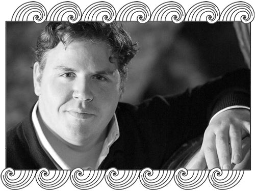 Thibault Liger-Belair, Côte de Nuits winemaker, beside a barrel in his cellar, framed with Dynamic Cellars wave design