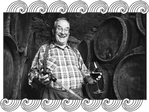 Henri Bonneau in his Châteauneuf-du-Pape cellar, wine thief and glass in hand, framed with Dynamic Cellars wave design