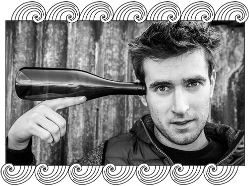 Milan Nestarec, Czech natural winemaker, holding a bottle, framed with Dynamic Cellars wave design