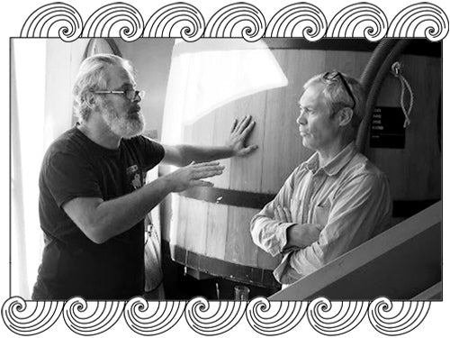 Ormiale Fabrice Domercq, Bordeaux winemakers discussing beside a large barrel, framed with Dynamic Cellars wave design