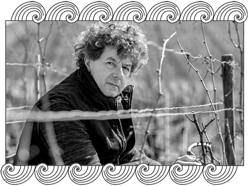 Philippe Pacalet pruning vines in his Burgundy vineyard in winter, framed with Dynamic Cellars wave design