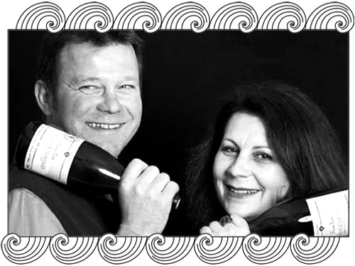 Philippe Valette, Burgundy winemakers duo, holding bottles of their biodynamic wines, framed with Dynamic Cellars wave design