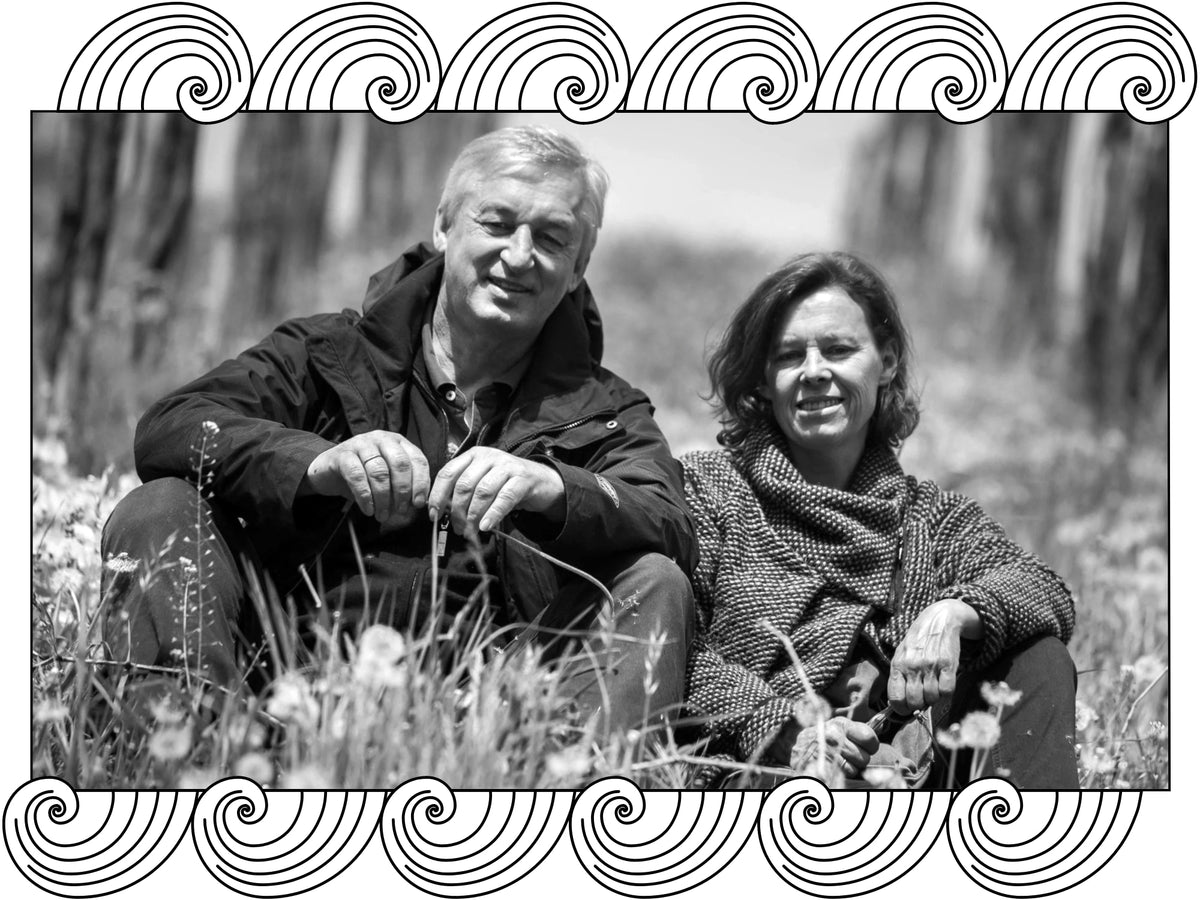 Weingut Maria & Sepp Muster: the couple seated among grasses in their vineyard, framed with Dynamic Cellars wave design